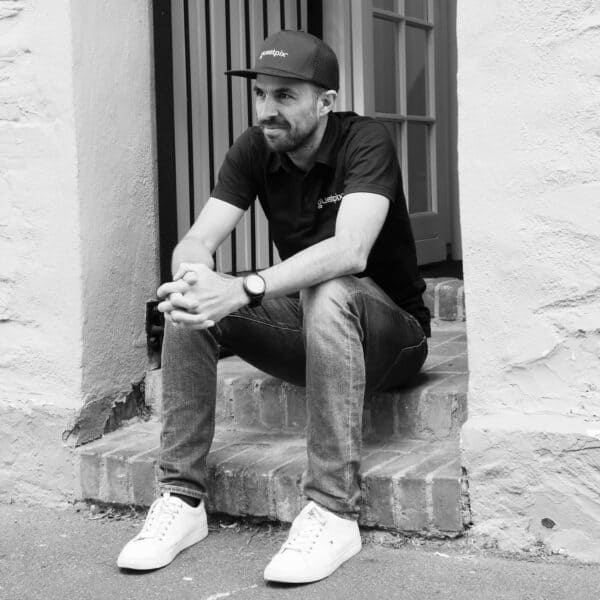 Young man sitting on a brick step outside a building.