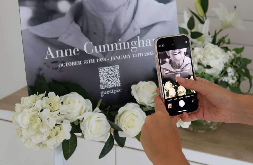 Person scanning memorial QR code on photo of Anne Cunningham.
