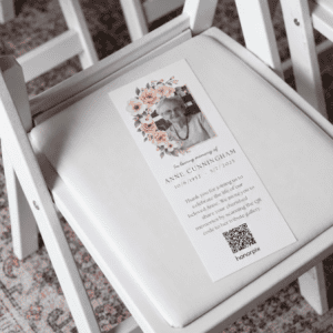 Tarjeta conmemorativa con una foto y un código QR sobre una silla blanca.