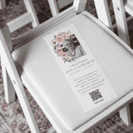 Memorial card with photo and QR code on a white chair.