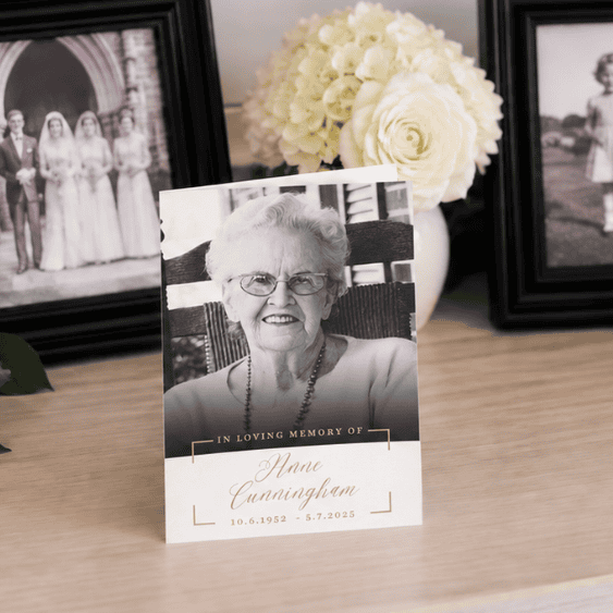 Memorial card of Hane Cunninghame with flowers and framed photos in background.
