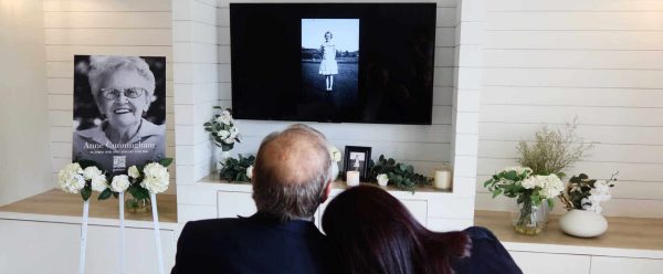 Family viewing memorial slideshow on TV for remembrance.
